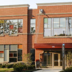 A section of a two-story, brick-fronted building with a red awning over the doors. The building is the Schoenbaum Family Center in Columbus, Ohio, home to Ohio State University's Crane Center for Early Childhood Research and Policy and the A. Sophie Rogers School for Early Learning.