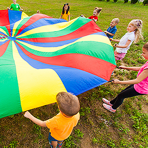 A view from above of children on the ground stretching a colorful parachute cloth