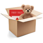 A cardboard box, inside of which are a children's book and a teddy bear