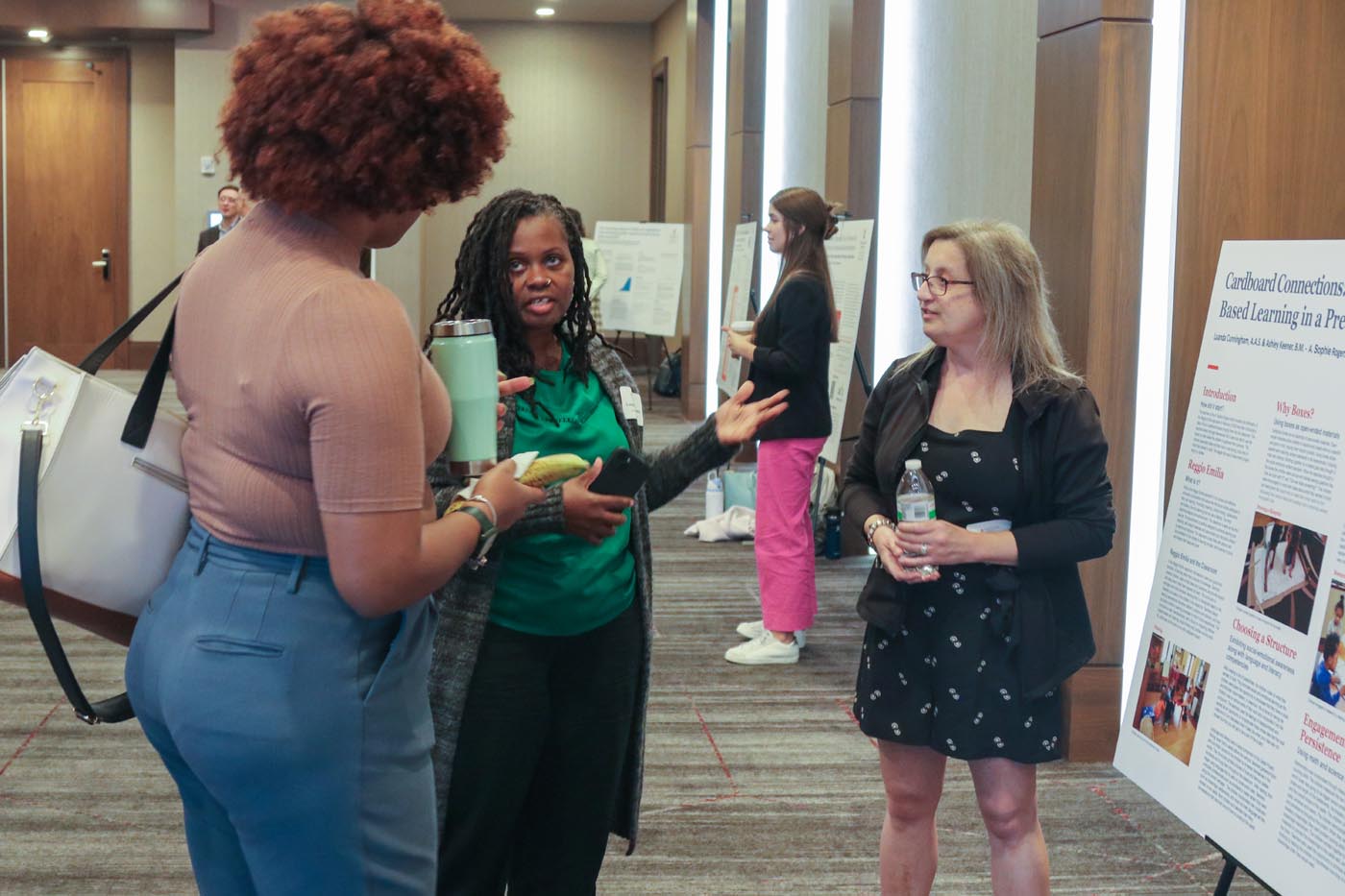 ASR teachers Luanda Cunningham, center, and Ashley Keener, right, talk to a symposium attendee about their classroom project