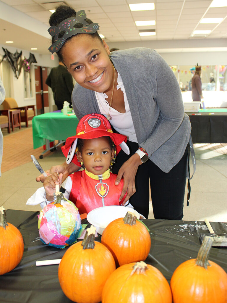 A woman stands next to a small child in costume